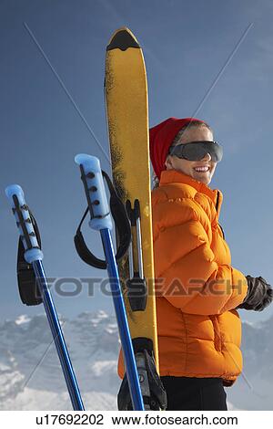 Stock Image - Woman smiling by ski and ski poles. Fotosearch