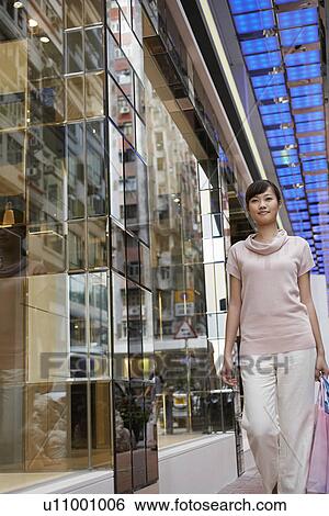 Stock Photograph - Woman walking past store in shopping mall. Fotosearch
