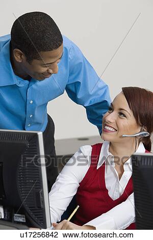 Stock Image - Woman Wearing Headset Chatting with Colleague. Fotosearch
