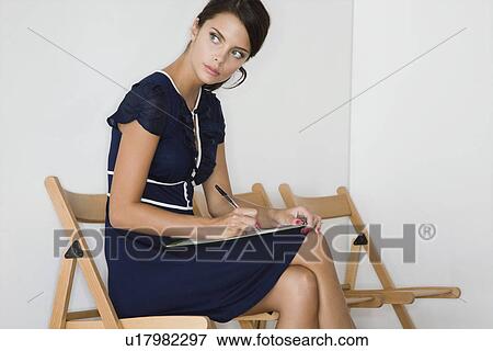 Stock Photo - Woman writing looking away. Fotosearch