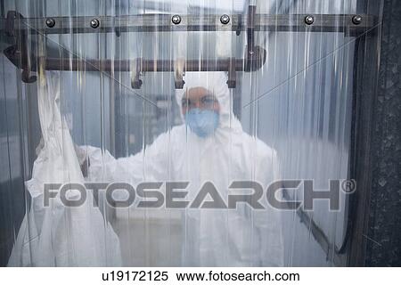 Stock Photography - Worker in protective mask and suit behind plastic wall. Fotosearch