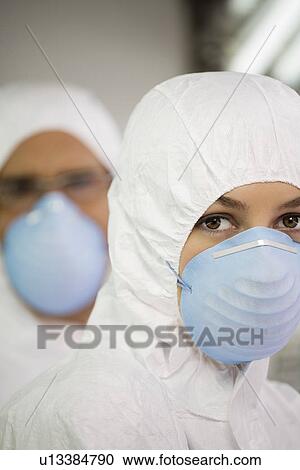 Stock Image - Workers in protective masks and suits portrait close up. Fotosearch