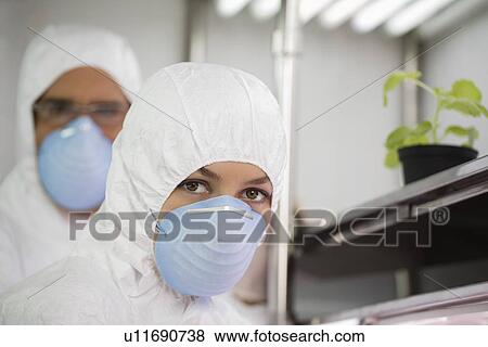 Stock Photo - Workers in protective masks and suits in laboratory portrait. Fotosearch