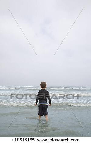 Young Boy Standing in Surf View Large Photo Image Stock Photography - Young Boy Standing in Surf. Fotosearch