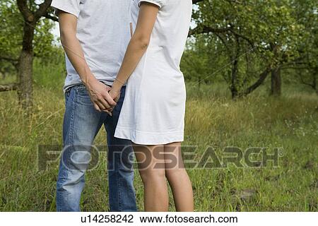 Stock Image - Young couple holding hands in orchard. Fotosearch