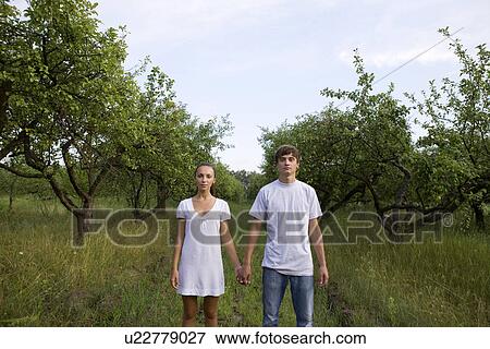 Young couple holding hands in orchard View Large Photo Image Stock Photo - Young couple holding hands in orchard. Fotosearch