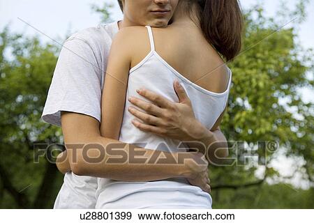 Stock Photo - Young couple hugging in orchard. Fotosearch