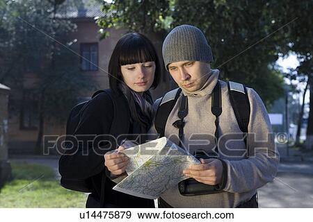 Stock Photo - Young couple reading map outdoors. Fotosearch
