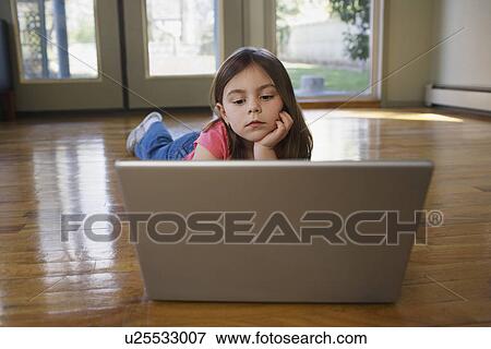 Young girl (5-6) lying on floor using laptop View Large Photo Image Stock Photo - Young girl (5-6) lying on floor using laptop. Fotosearch
