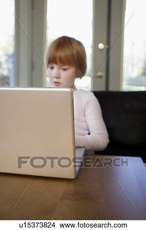 Picture - Young girl (5-6) using laptop concentrated. Fotosearch