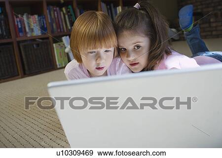 Young girls (5-6) lying on floor using laptop contemplating View Large Photo Image Stock Photo - Young girls (5-6) lying on floor using laptop contemplating. Fotosearch