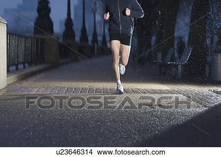 Young man jogging on city pavement at dawn in London View Large Photo Image Picture - Young man jogging on city pavement at dawn in London. Fotosearch