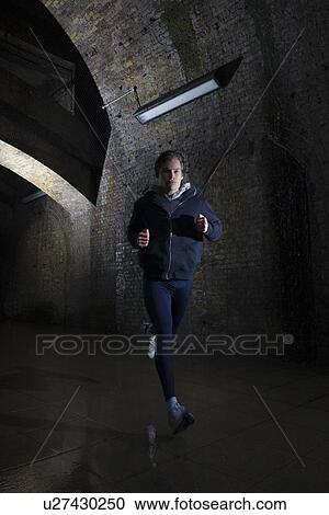 Young man jogging through urban tunnel at night View Large Photo Image Stock Image - Young man jogging through urban tunnel at night. Fotosearch