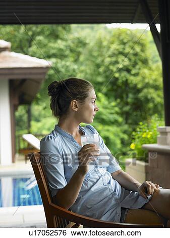 Stock Photograph - Young Woman Beneath Veranda with Glass of Water. Fotosearch