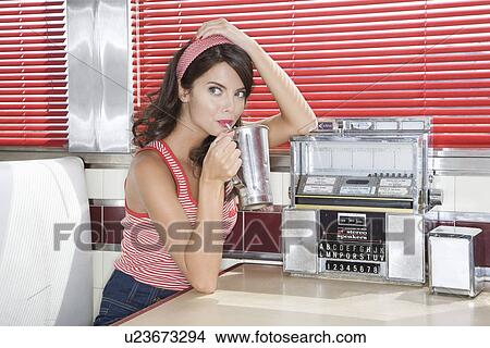 Picture - Young Woman Drinking a Milkshake in a Diner. Fotosearch