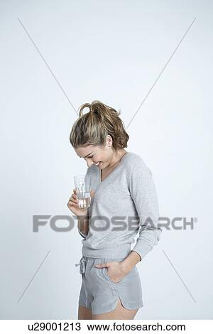 Young woman holding glass of water smiling View Large Photo Image Stock Image - Young woman holding glass of water smiling. Fotosearch