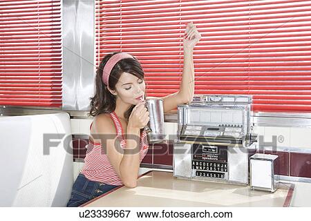 Stock Photo - Young Woman in a Diner Booth Drinking a Shake. Fotosearch