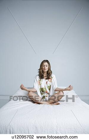 Young woman in dressing gown meditating in bed View Large Photo Image Stock Image - Young woman in dressing gown meditating in bed. Fotosearch