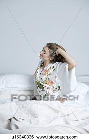 Young woman in dressing gown stretching in bed View Large Photo Image Stock Photograph - Young woman in dressing gown stretching in bed. Fotosearch