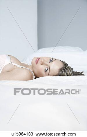 Stock Image - Young woman in underwear lying on bed close-up. Fotosearch