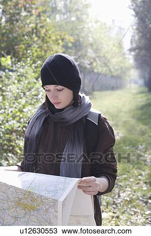 Stock Image - Young woman in winter clothes reading map. Fotosearch