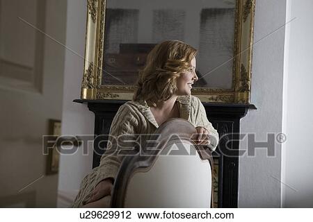 Stock Image - Young woman leaning on chair. Fotosearch