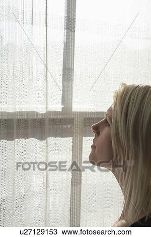 Young woman looking through window close-up View Large Photo Image Stock Image - Young woman looking through window close-up. Fotosearch