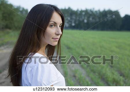 Stock Image - Young woman standing on field. Fotosearch