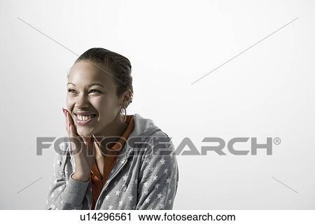 Stock Image - Young woman touching her cheek smiling close-up view. Fotosearch