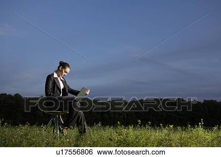 Young woman using laptop in field View Large Photo Image Stock Photograph - Young woman using laptop in field. Fotosearch