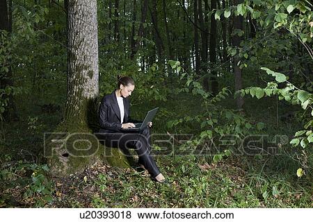 Young woman using laptop in forest View Large Photo Image Stock Photo - Young woman using laptop in forest. Fotosearch