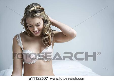Young woman wearing bra smiling on bed View Large Photo Image Stock Photo - Young woman wearing bra smiling on bed. Fotosearch