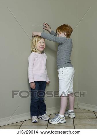 7-8 byear old measures height difference with 4-5 year old View Large Photo Image Picture - 7-8 byear old measures height difference with 4-5 year old. Fotosearch