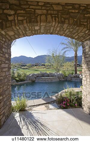 Stock Image - Arch overviewing swimming pool by luxurious residence. Fotosearch