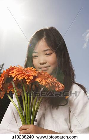 Stock Image - Asian girl holding bunch of flowers. Fotosearch