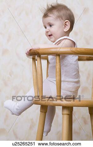 Stock Image - Baby boy sitting on high chair laughing. Fotosearch