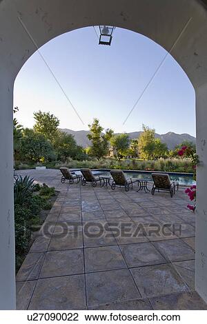 Stock Image - Back yard with deckchairs and swimming pool sunset. Fotosearch