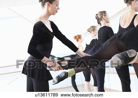 Ballet teacher adjusting foot position at the barre View Large Photo Image Stock Photo - Ballet teacher adjusting foot position at the barre. Fotosearch