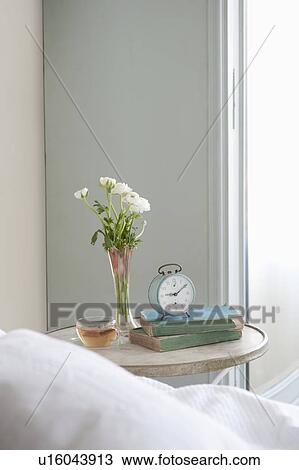 Bedside table with cut flower and alarm clock View Large Photo Image Stock Image - Bedside table with cut flower and alarm clock. Fotosearch