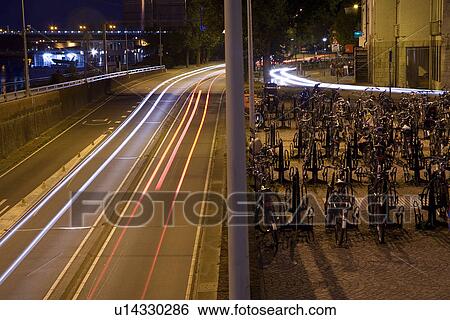 Bicycles parked by busy highway View Large Photo Image Stock Photograph - Bicycles parked by busy highway. Fotosearch