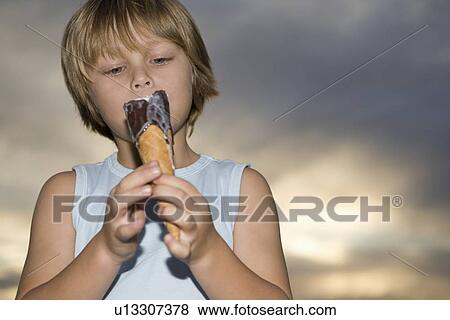 Blonde 7-8 year old boy in vest top holds melting chocolate ice cream View Large Photo Image Stock Photo - Blonde 7-8 year old boy in vest top holds melting chocolate ice cream. Fotosearch