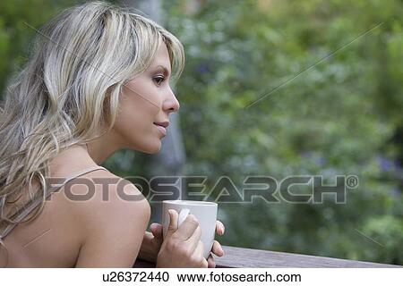 Blonde woman sits with cup on garden veranda View Large Photo Image Stock Image - Blonde woman sits with cup on garden veranda. Fotosearch