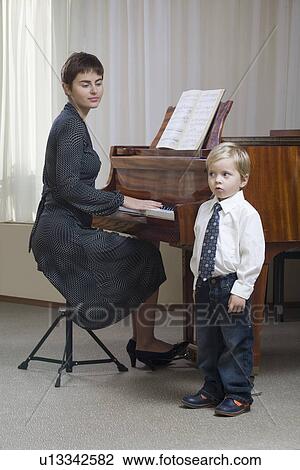 Boy (3-4) singing accompanied by teacher playing piano View Large Photo Image Stock Image - Boy (3-4) singing accompanied by teacher playing piano. Fotosearch