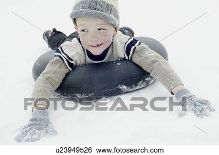 Boy in winter clothing sledging on an inner tyre View Large Photo Image Stock Photograph - Boy in winter clothing sledging on an inner tyre. Fotosearch