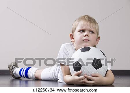 Picture - Boy lying on floor and holding soccer ball portrait. Fotosearch
