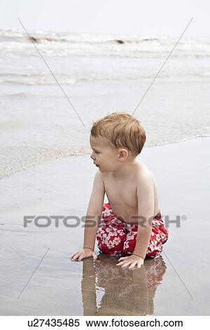 Stock Photography - Boy on hands and knees in water from sea. Fotosearch