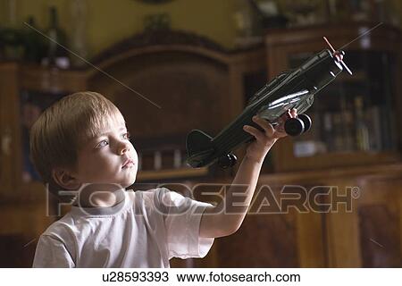 Boy playing with model airplane in home View Large Photo Image Stock Image - Boy playing with model airplane in home. Fotosearch