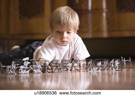 Stock Photograph - Boy playing with toy soldiers on floor. Fotosearch