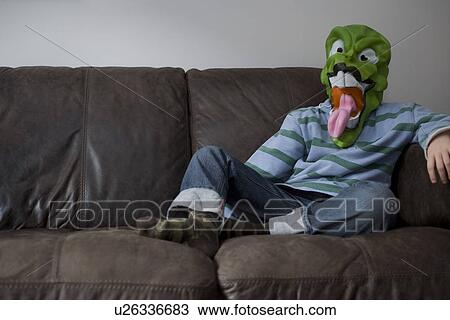 Stock Image - Boy wearing mask on sofa. Fotosearch