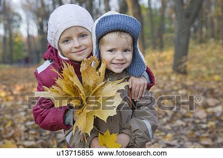 Stock Photography - Brother and sister holding leaves in park portrait. Fotosearch